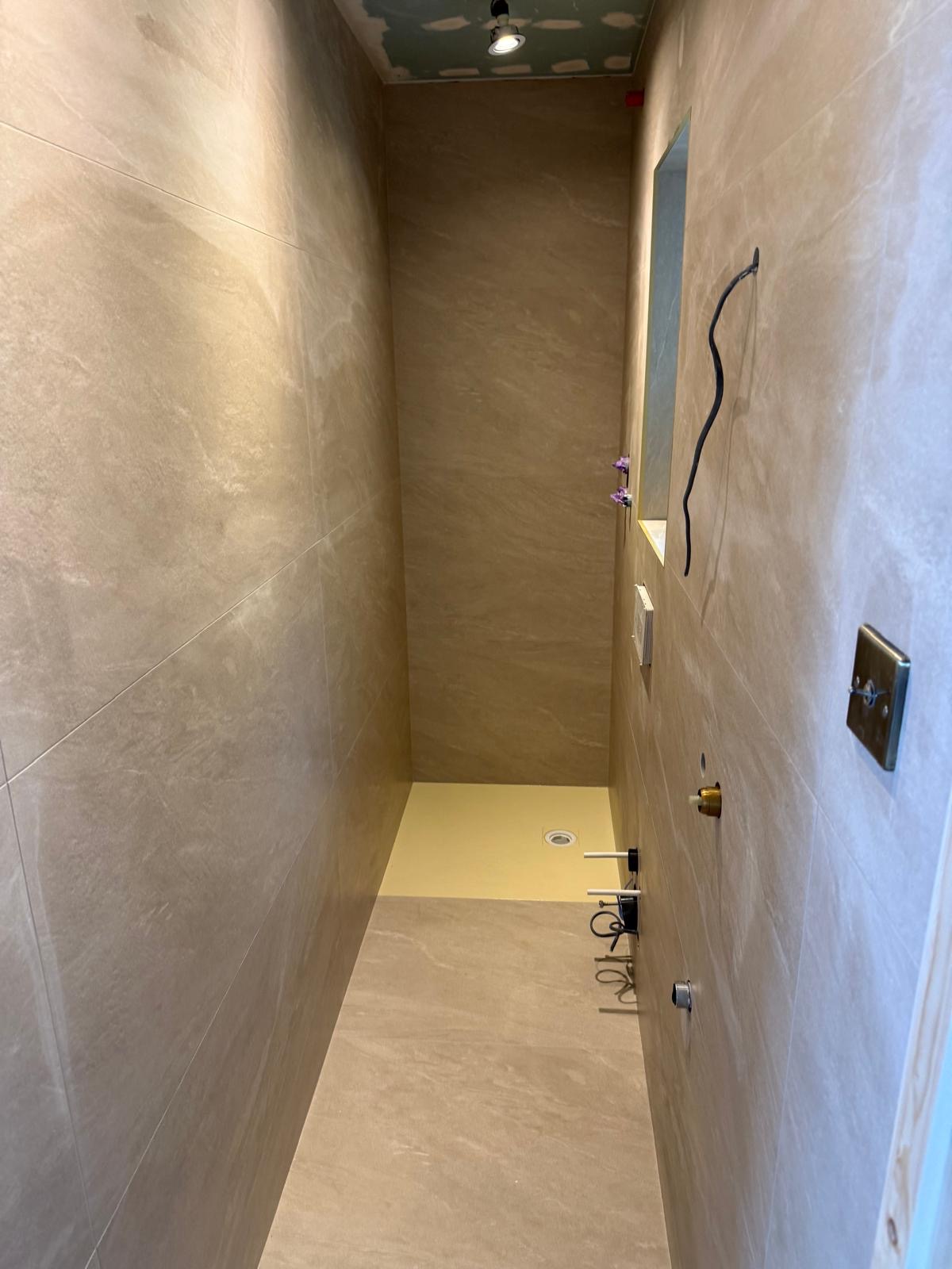 Walk in shower tiling with large wall tiles and shower tray area